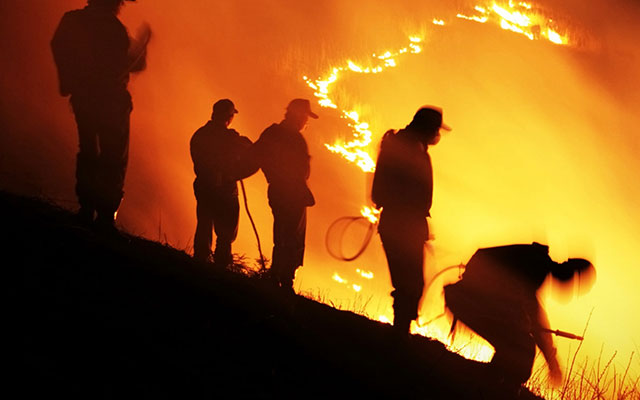 Wildfire firefighters working at night on the edge of a fire.